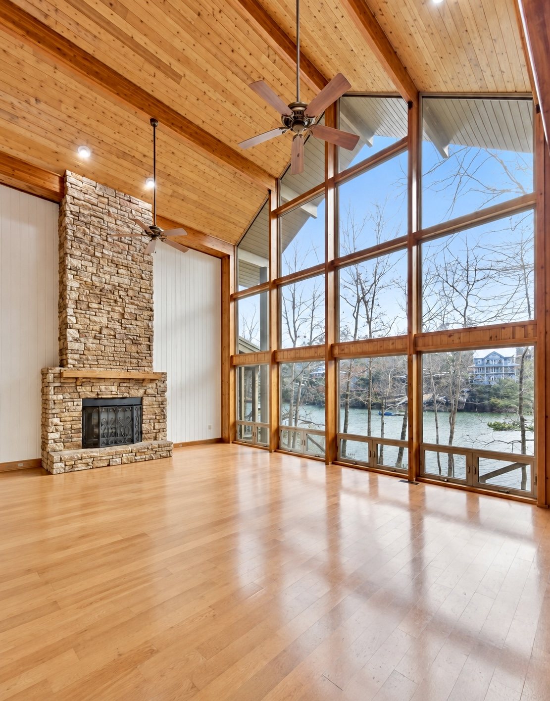 Lindal cedar great room with soaring vaulted wood ceiling, stone fireplace and floor-to-ceiling windows overlooking Smith Lake
